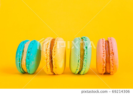 Sweet almond colorful unicorn pink blue yellow green macaron or macaroon dessert cake isolated on trendy yellow modern fashion background. French sweet cookie. Minimal food bakery concept Copy space Sweet almond colorful unicorn pink blue yellow green macaron or macaroon dessert cake isolated on trendy yellow modern fashion background. French sweet cookie. Minimal food bakery concept Copy space 69214306