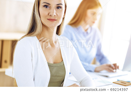 Business woman portrait at sunny office. Businesspeople or colleagues discussing something at meeting while sitting at the desk in office. Casual clothes style. Audit, tax or lawyer concept 69214397