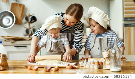 Mother and kids preparing pastry together. Mother and kids preparing pastry together. 69215154