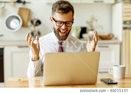 Happy businessman getting great news on laptop at Happy businessman getting great news on laptop at 69215155