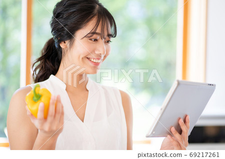使用片劑的一名婦女在廚房裡 使用片劑的一名婦女在廚房裡 69217261