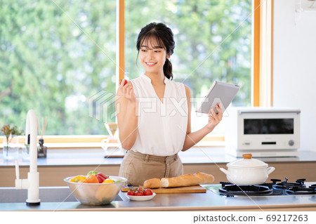 使用片劑的一名婦女在廚房裡 使用片劑的一名婦女在廚房裡 69217263
