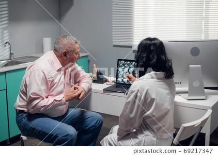 Senior patient listening to the doctors explanation of what she sees on the x-ray Senior patient listening to the doctors explanation of what she sees on the x-ray 69217347