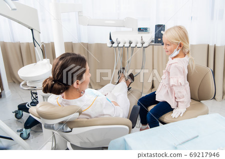 An experienced dentist is talking to the girl trying to set up a An experienced dentist is talking to the girl trying to set up a 69217946