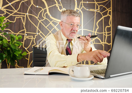 Indignant entrepreneur recording voice message Indignant entrepreneur recording voice message 69220784