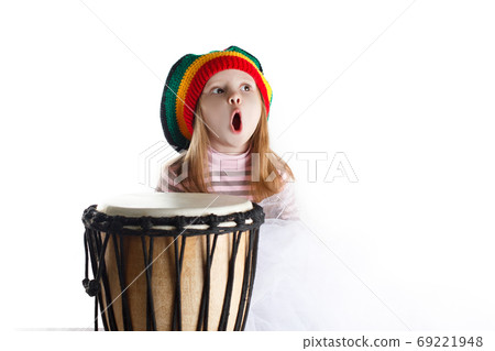 Expressive toddler girl portrait in rastafarian hat with drum 69221948