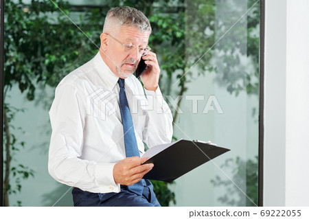 Businessman reading document on clipboard Businessman reading document on clipboard 69222055