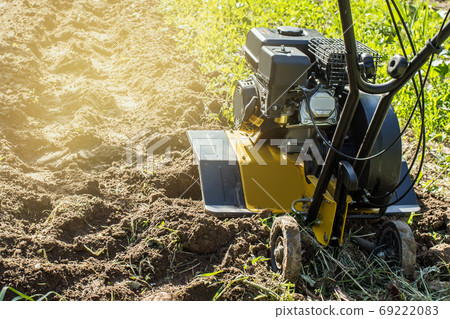 Motor cultivator fresh raw in garden soil 69222083