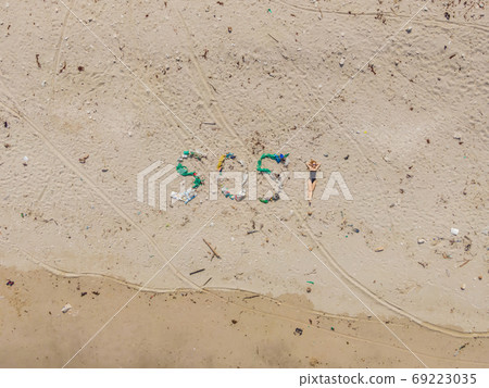 SOS inscription and woman sunbathes on the beach nearby. Environmental problem. Ecology concept. Plastic on the beach with sos writing. Spilled garbage on the beach SOS inscription and woman sunbathes on the beach nearby. Environmental problem. Ecology concept. Plastic on the beach with sos writing. Spilled garbage on the beach 69223035