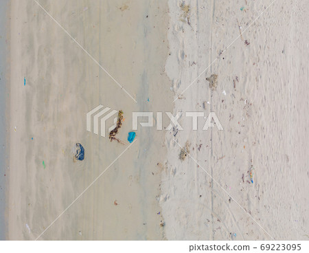 Sandy beach with Plastic garbage and medical waste materials in tropical beach with emerald clear sea - Aerial top view photo taken by drone 69223095