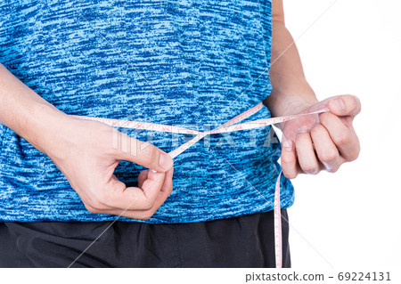 Chubby man measuring his waist with white measuring tape isolated on white background. 69224131