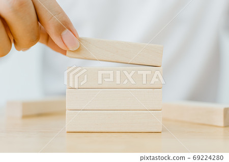 Hand arranging wood block stacking on top with wooden table Hand arranging wood block stacking on top with wooden table 69224280