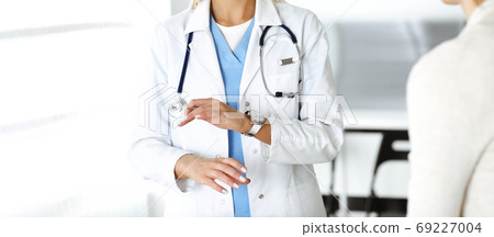 Unknown woman-doctor communicating with female patient. Physician checks medical history record and exam results, close-up. Medicine concept 69227004