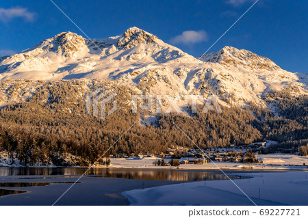 View of beautiful snow mountains behind Lake Silvaplana and its View of beautiful snow mountains behind Lake Silvaplana and its 69227721