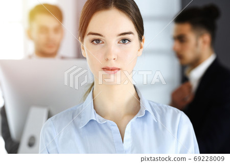 Business woman and group of diverse business people at the background in sunny office Business woman and group of diverse business people at the background in sunny office 69228009