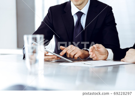 Business people using tablet computer while working together in modern office. Unknown businessman with colleague at workplace. Teamwork and partnership concept Business people using tablet computer while working together in modern office. Unknown businessman with colleague at workplace. Teamwork and partnership concept 69228297