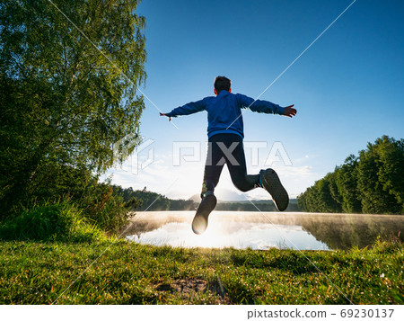 Jumping short hair boy at mountain lake makes fun Jumping short hair boy at mountain lake makes fun 69230137