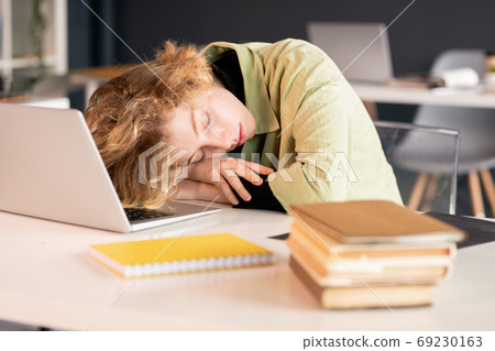 Young exhausted female student or office manager keeping head on hands 69230163