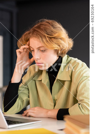 Young serious female developer of software looking through online information Young serious female developer of software looking through online information 69230164