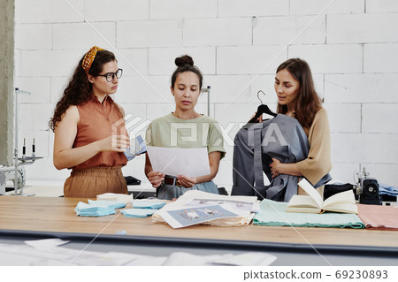Pretty creative designer or tailor showing colleagues fashion sketch 69230893