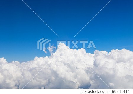 Above clouds from airplane window with blue sky Above clouds from airplane window with blue sky 69231415