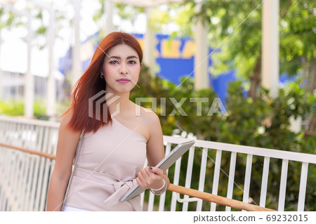 asian young beautiful businesswoman happy holding laptop in modern outdoor office. asian young beautiful businesswoman happy holding laptop in modern outdoor office. 69232015