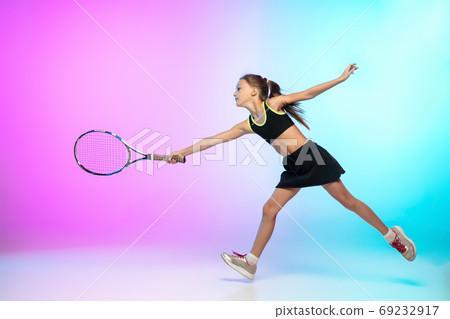 Little tennis girl in black sportwear isolated on gradient background in neon light Little tennis girl in black sportwear isolated on gradient background in neon light 69232917