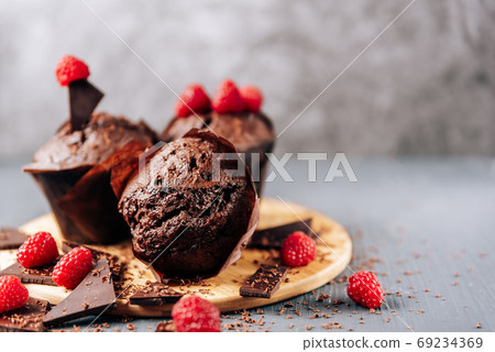chocolate cupcakes with raspberries and bitter chocolate close-up on a light background 69234369