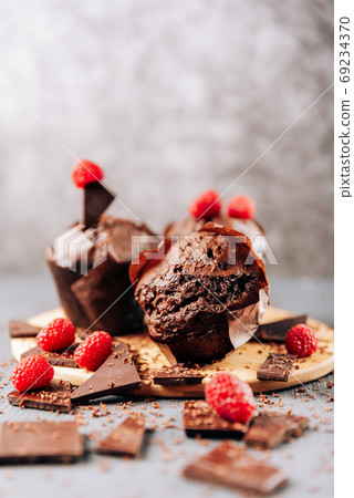 chocolate cupcakes with raspberries and bitter chocolate close-up on a light background 69234370