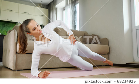 woman does sports exercises standing in side plank on floor 69234929