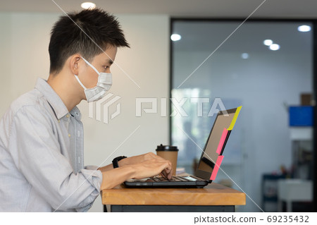 Business man working job on labtop and wering mask in office. 69235432