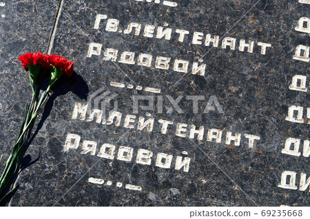 flowers on the memorial to fallen soldiers, red carnations on black marble, Russian text of soldiers military rank - sergeant,major, colonel,Lieutenant Colonel, private, corporal flowers on the memorial to fallen soldiers, red carnations on black marble, Russian text of soldiers military rank - sergeant,major, colonel,Lieutenant Colonel, private, corporal 69235668