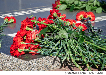 flowers on the memorial to fallen soldiers, red carnations on black marble, Russian text - monument to the unknown soldier 69235681