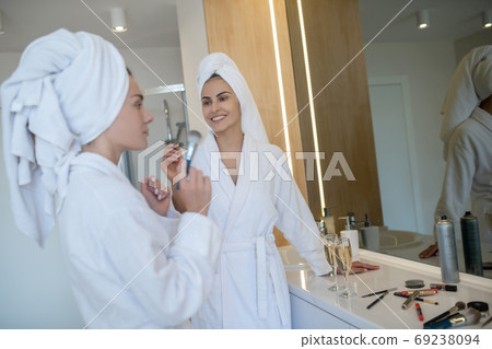 Two pretty girls doing make up after bath Two pretty girls doing make up after bath 69238094