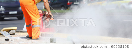 Male worker holds gas cutter in his hands and cuts concrete. Male worker holds gas cutter in his hands and cuts concrete. 69238198