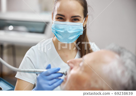 Beautiful female dentist using a dental drill Beautiful female dentist using a dental drill 69238639