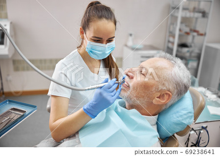 Qualified female dentist treating an elderly patient Qualified female dentist treating an elderly patient 69238641