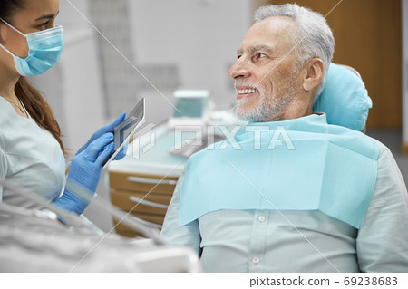Eldelry citizen sitting in a dental chair near his dentist Eldelry citizen sitting in a dental chair near his dentist 69238683