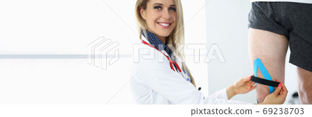 Female doctor fixes a sports tape on leg Female doctor fixes a sports tape on leg 69238703