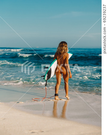 Naked surf girl with surfboard on ocean beach. Freedom concept Naked surf girl with surfboard on ocean beach. Freedom concept 69239237