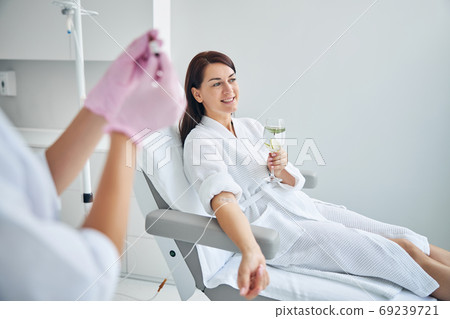 Smiling woman with a catheter in her vein looking away 69239721