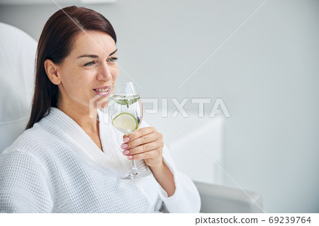 Smiling spa client with a glass of healthy drink 69239764