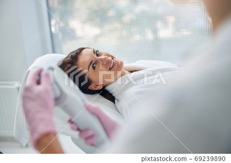 Dark-haired cheerful female patient in a beauty parlor Dark-haired cheerful female patient in a beauty parlor 69239890