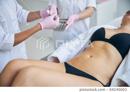 Two women preparing a patient for an injection 69240003