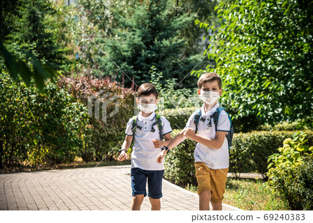 Happy schoolchildren with face masks run from the joy of returning to school during the Covid-19 Happy schoolchildren with face masks run from the joy of returning to school during the Covid-19 69240383