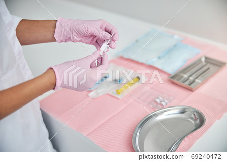 Professional cosmetologist preparing for administering an injection Professional cosmetologist preparing for administering an injection 69240472