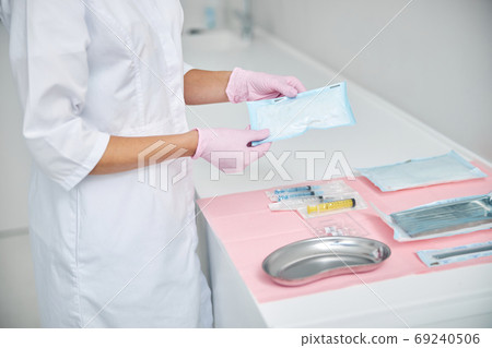 Female dermatologist preparing for performing a medical procedure Female dermatologist preparing for performing a medical procedure 69240506