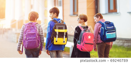 Children with rucksacks standing in the park near school 69240789