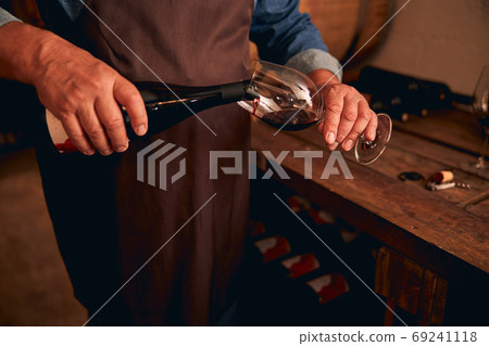 Male sommelier hands pouring glass of red wine 69241118