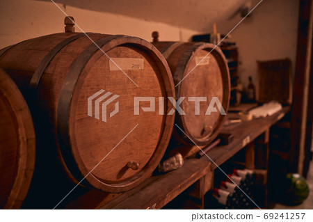 Traditional oak barrels with wine in storage room Traditional oak barrels with wine in storage room 69241257
